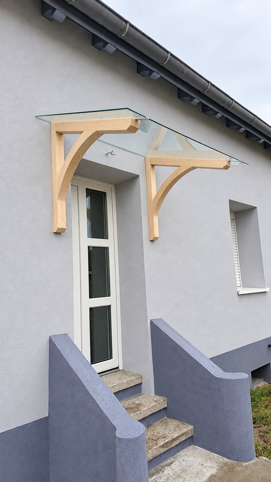 Auvent en bois et verre au-dessus d'une porte d'entrée