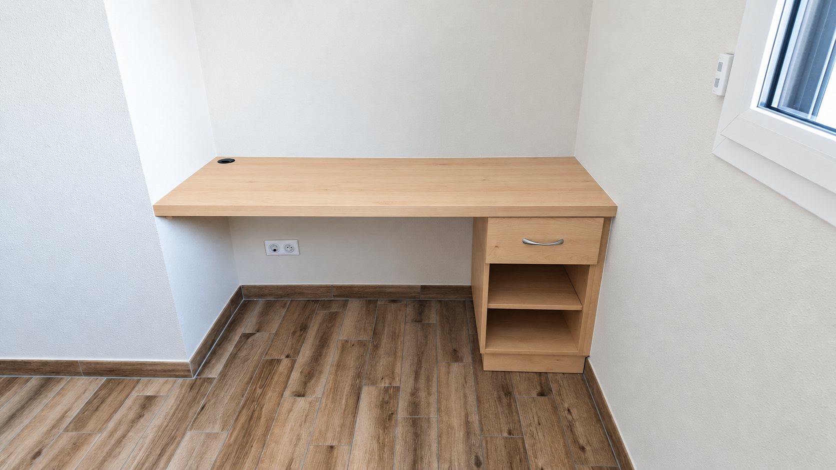 Bureau en bois clair avec tiroirs, installé sous un pan de toit