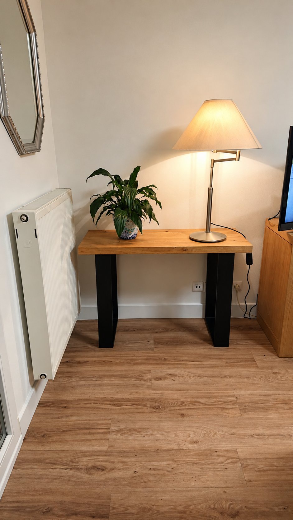 Console en bois à pieds noirs sur un parquet, avec une lampe