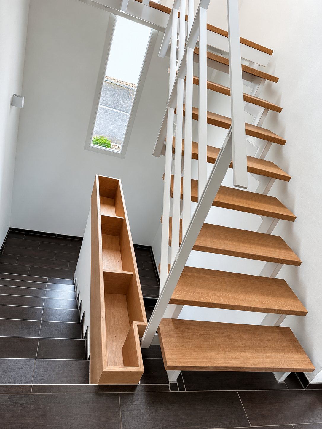 Escalier droit à marches en bois avec rangement latéral et fenêtre de toit