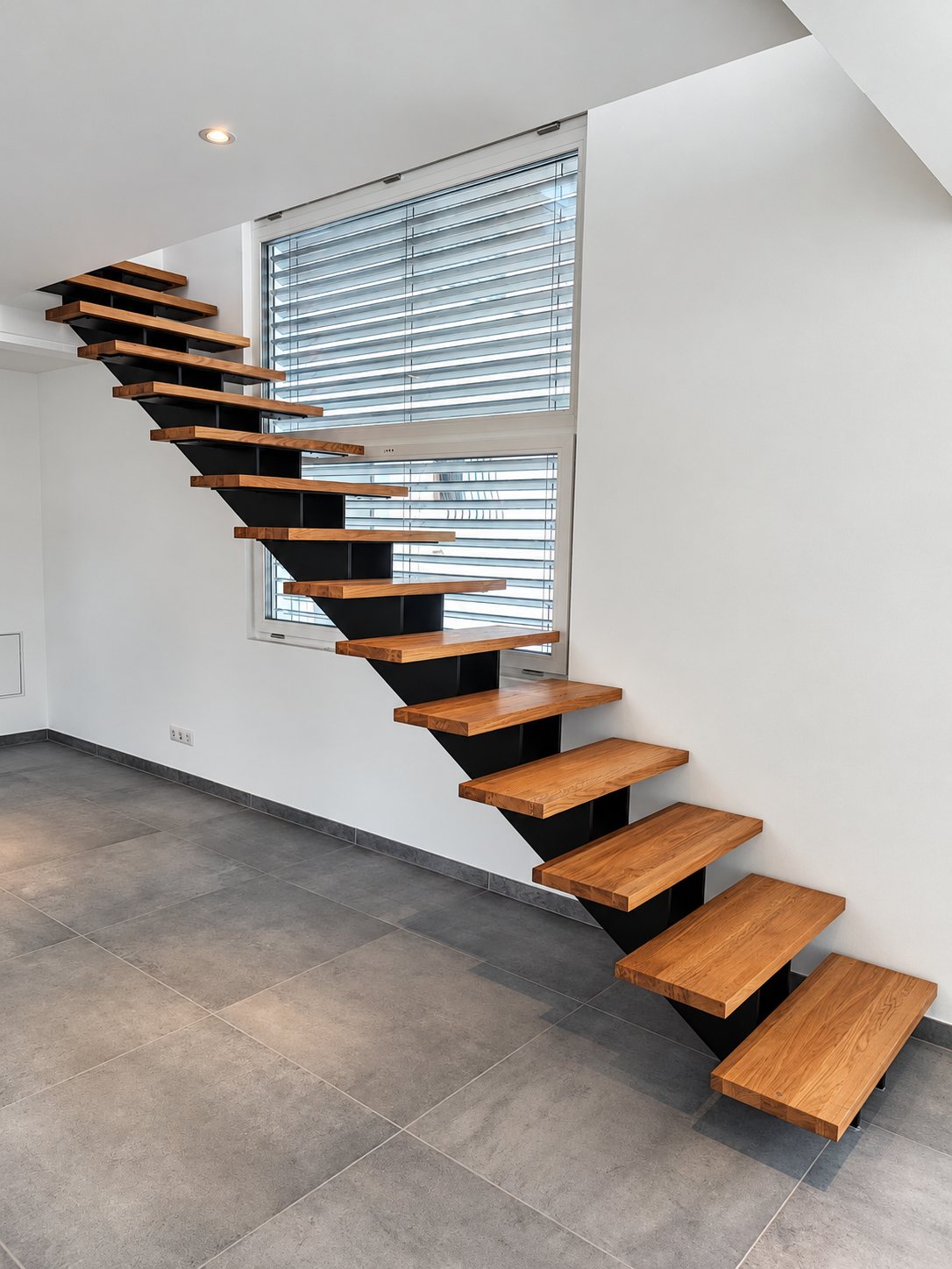 Escalier à limon métallique noir et marches en bois dans un salon carrelé