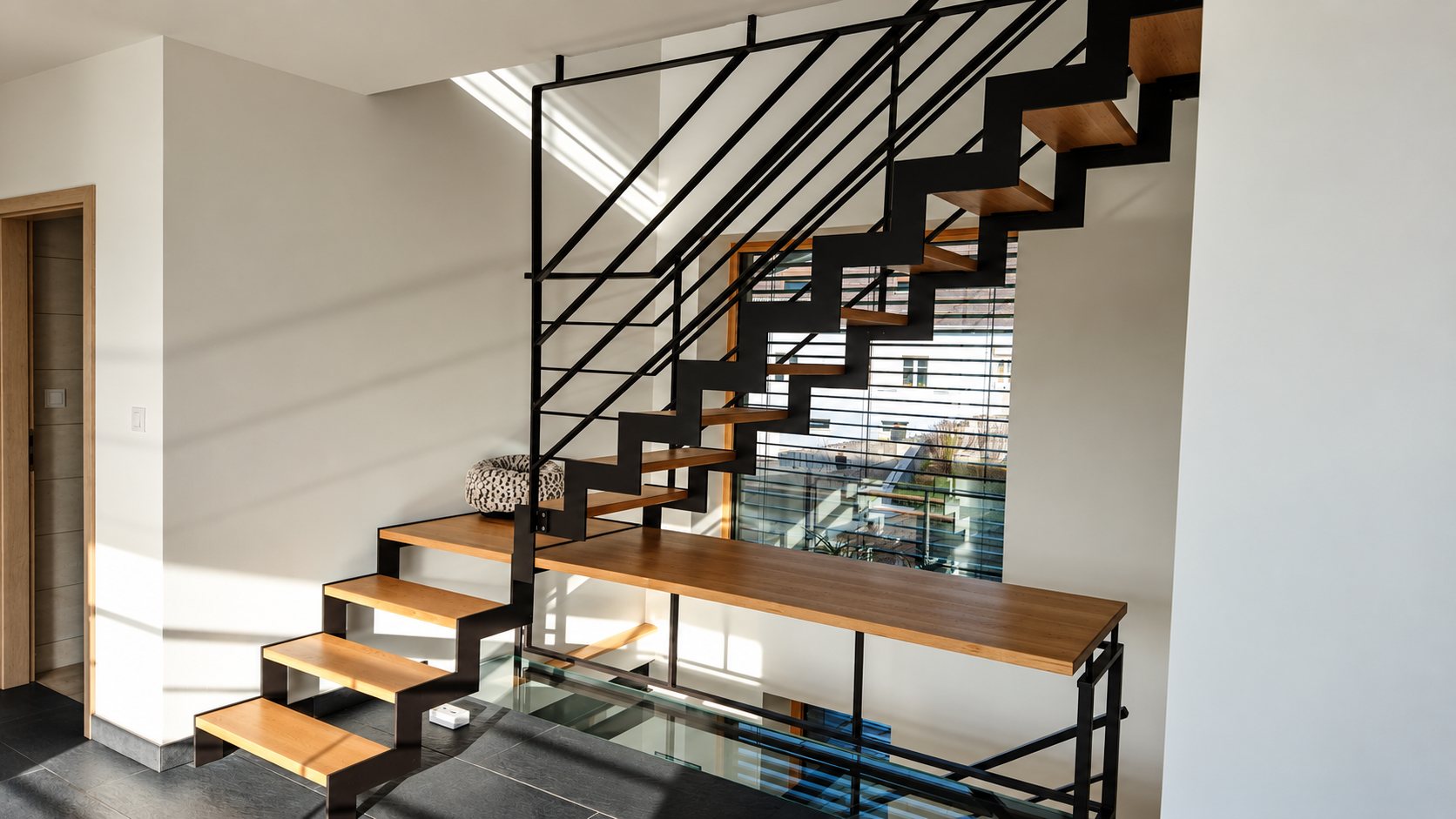 Escalier intérieur contemporain à structure métallique noire en zigzag, marches en bois clair et garde-corps à barres horizontales, baigné de lumière naturelle.