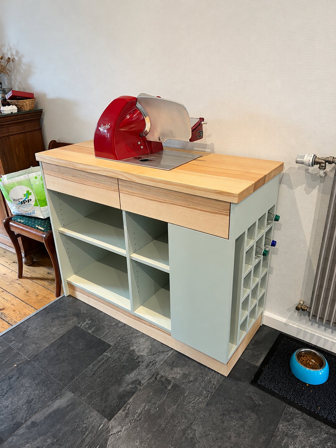 Petit meuble de cuisine à plateau en bois clair, tiroirs et casier à bouteilles