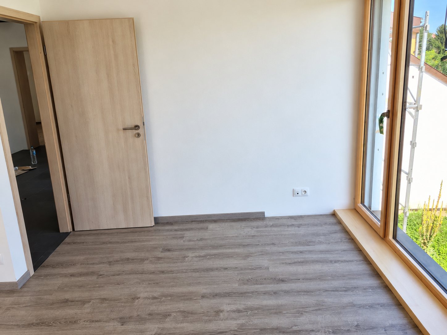 Pièce lumineuse au parquet gris et aux baies en bois