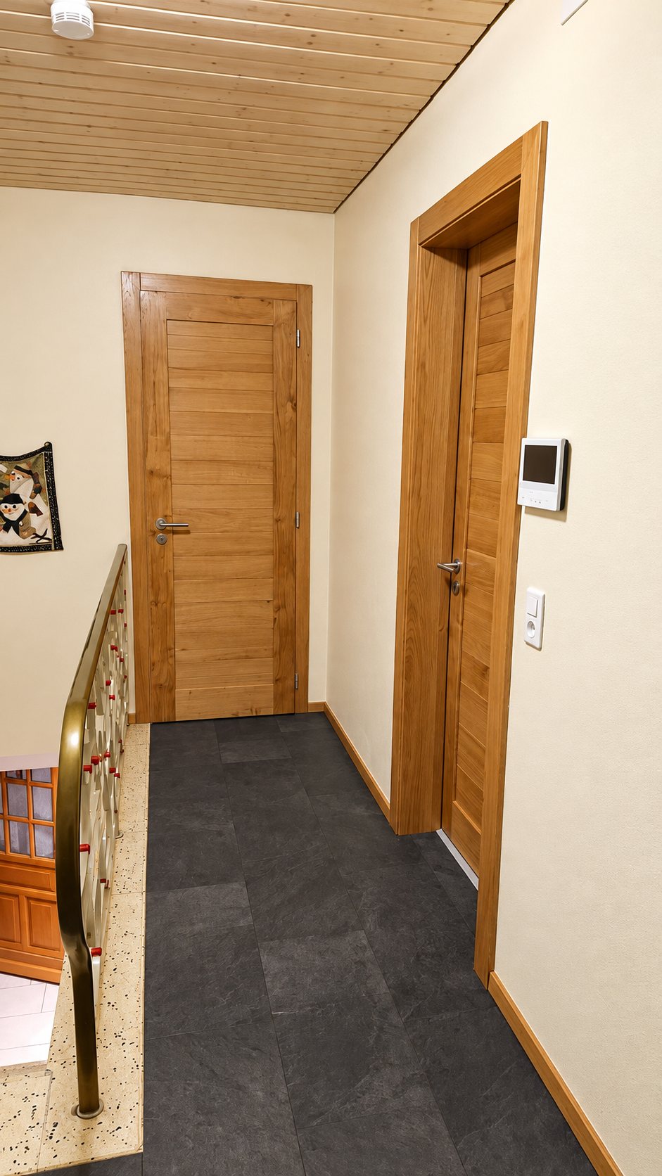 Porte en bois clair dans un couloir au sol en ardoise