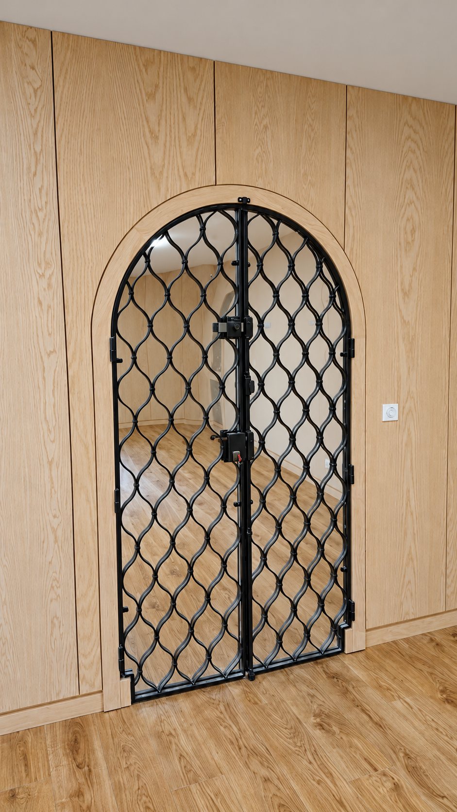 Porte cintrée à grille en fer forgé dans une boiserie en bois clair