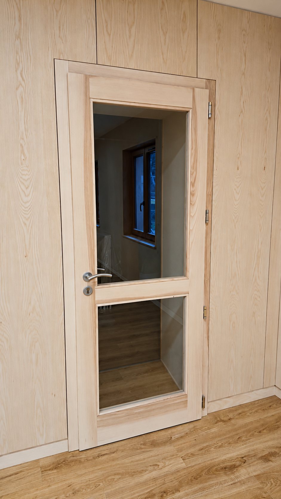 Porte en bois clair à deux vitrages, dans une boiserie