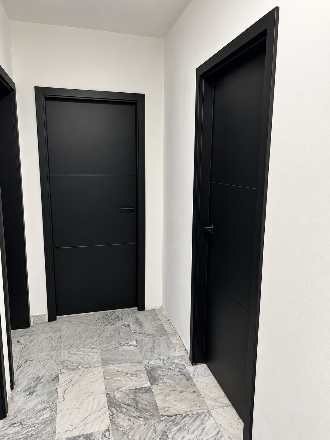 Deux portes noires sur mesure dans un couloir au sol en marbre