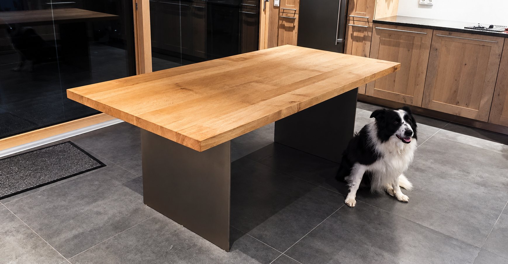 Table de cuisine en chêne à pied en acier, avec un chien assis à côté