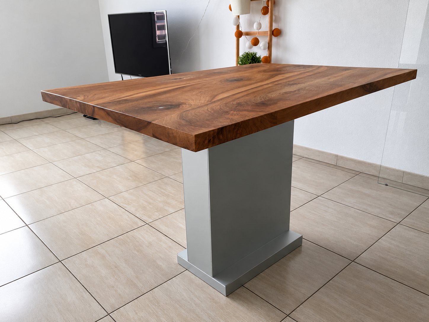 Table de cuisine à plateau en noyer et pied central, sur un carrelage clair